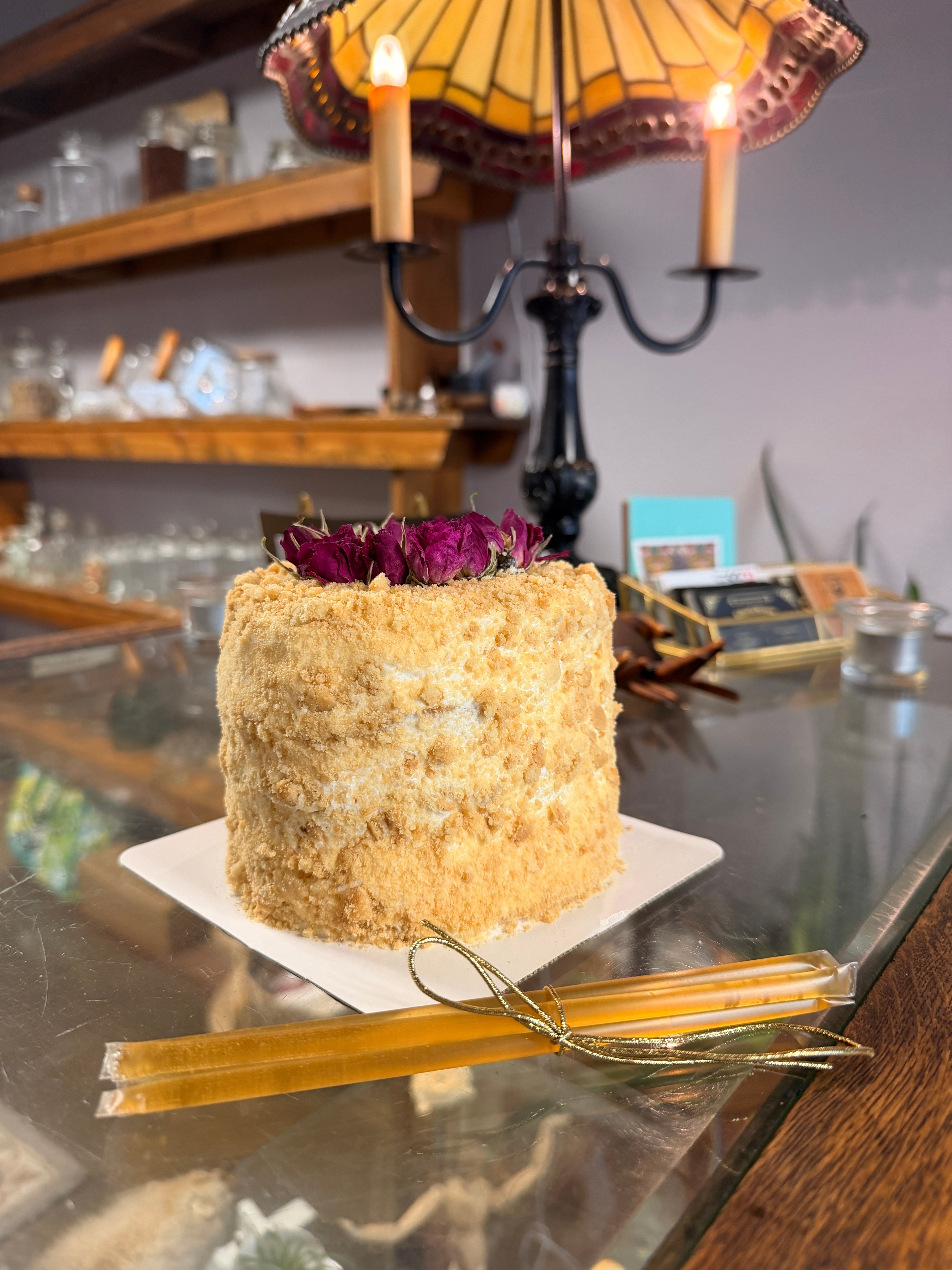5-inch honey cake covered in golden crumbs and topped with dried red roses